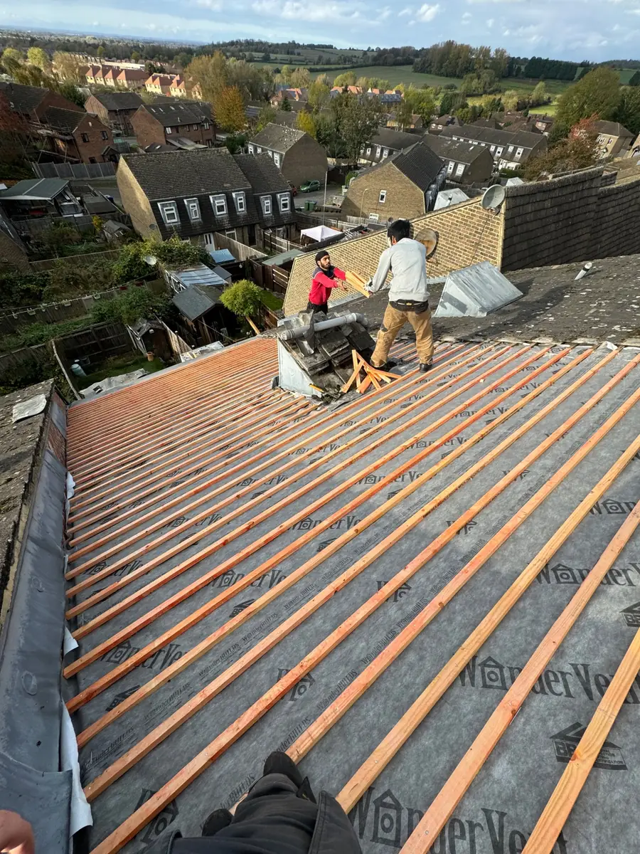 Re-roof in progress: battens on new membrane, two roofers cutting at the top of the roof