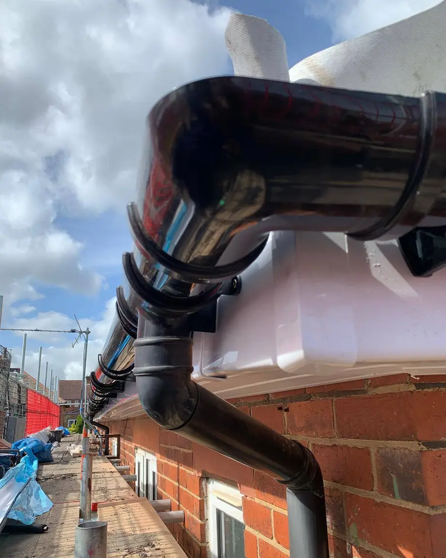 Black downpipe and gutter outlet at the corner of a roof