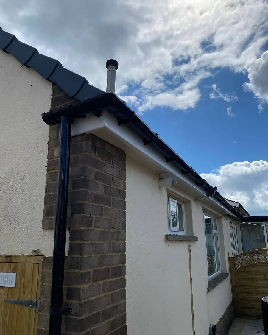 New black gutters and downpipe on a white rendered house