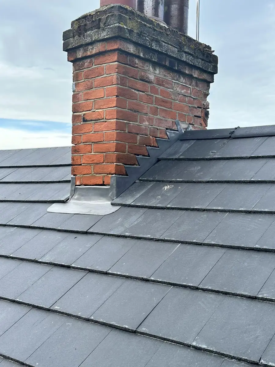 Brick chimney stack with new lead flashing on a grey tiled roof
