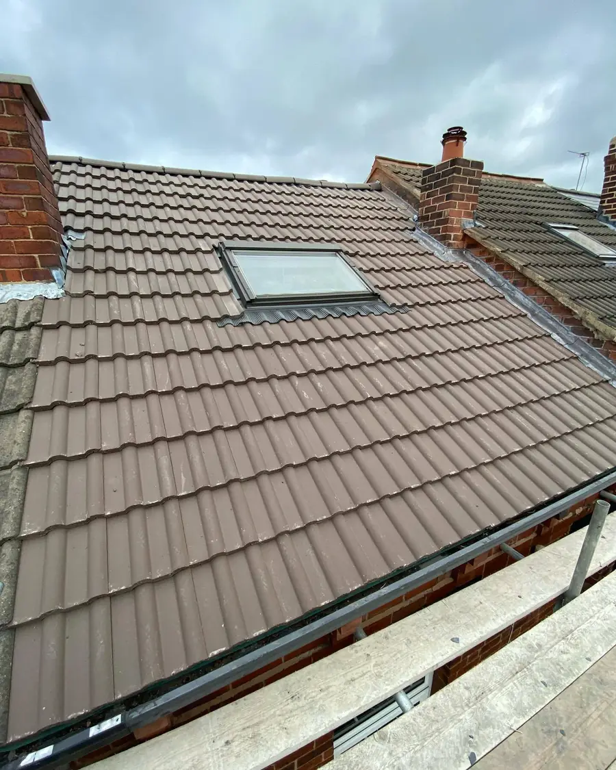 Brown tiled roof with a roof window and scaffold along the eaves