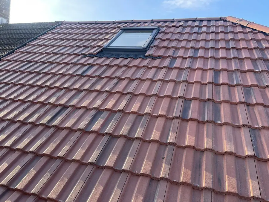 Brown and red tiled roof with a roof window, close up