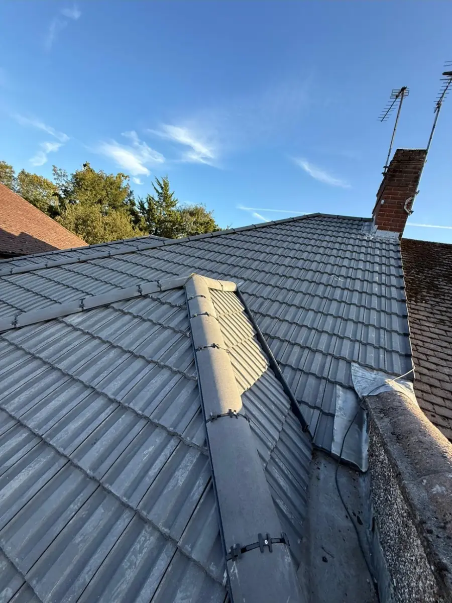 Dark grey tiled roof with a ridge line and a neighbouring chimney