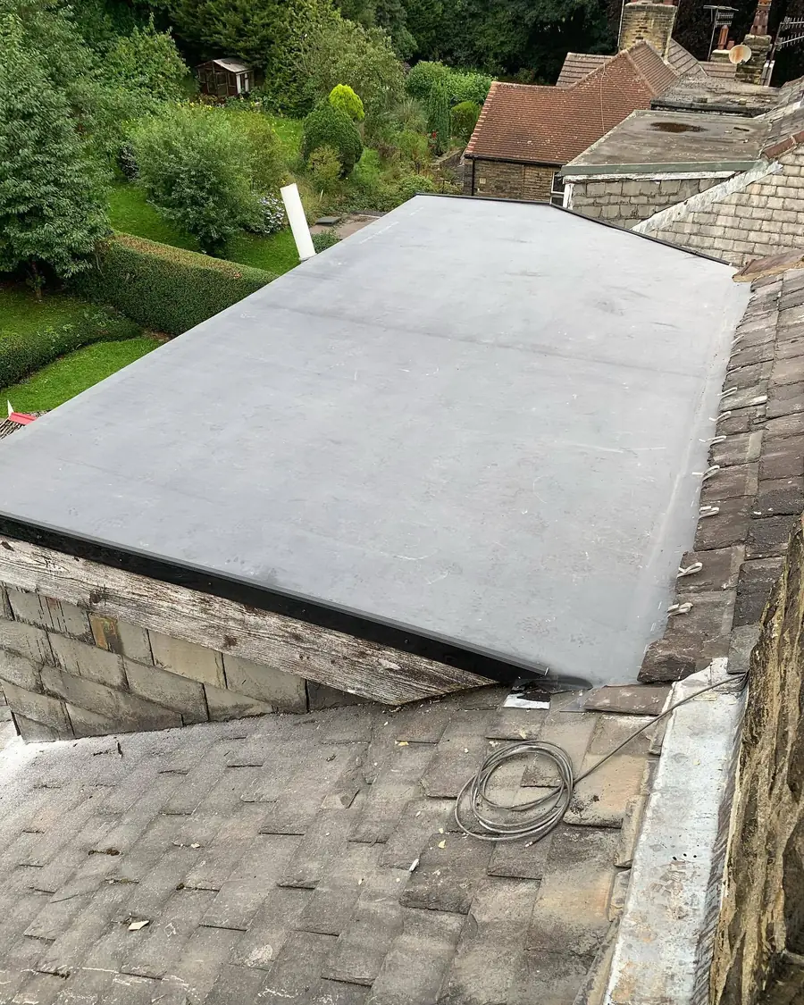 Grey single-sheet flat roof membrane dressed over the edge of an extension
