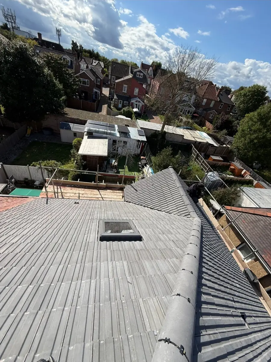 Grey concrete tiled roof with a roof window, looking out over back gardens