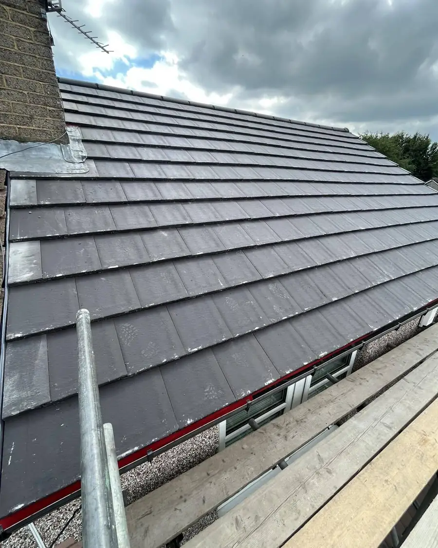 Grey tiled roof and scaffold against a cloudy sky