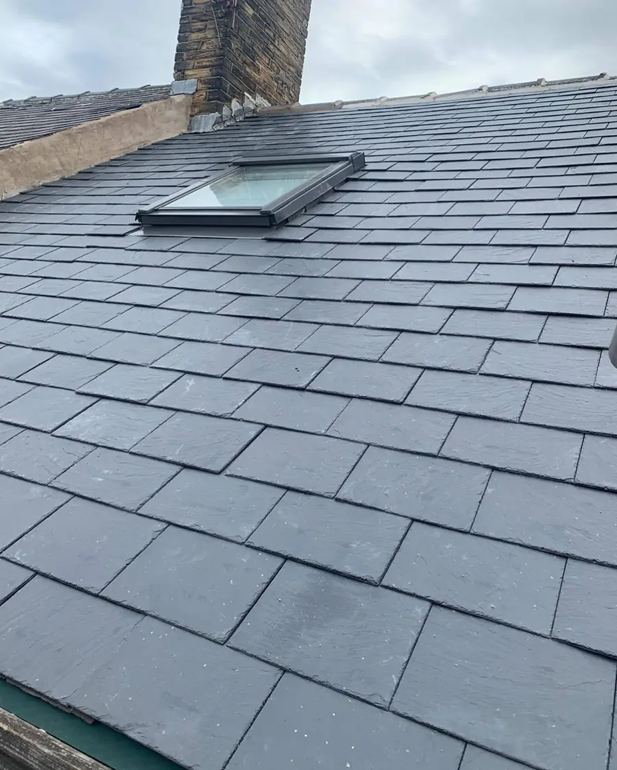Grey tiled roof with a roof window and a chimney