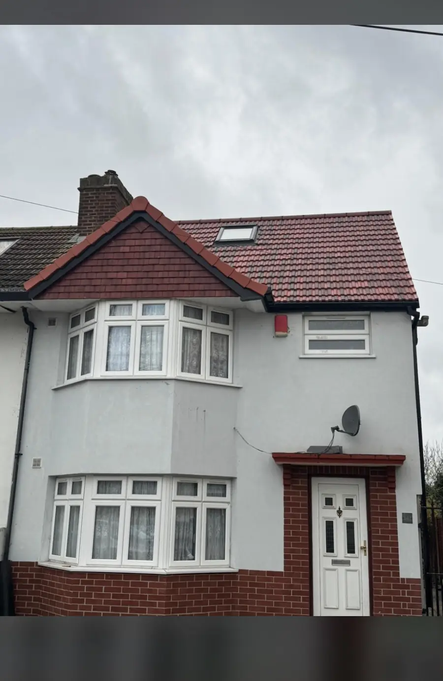 White rendered semi-detached house with a red tiled roof and a dormer, front view