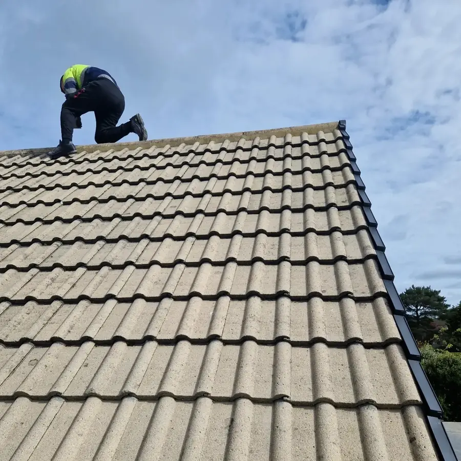 Roofer working on the ridge of a beige tiled roof