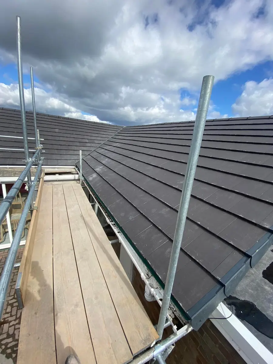 Scaffold walkway along the eaves of a newly tiled grey roof