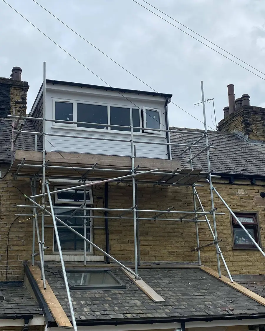 Scaffold around a stone house with a flat-roofed dormer